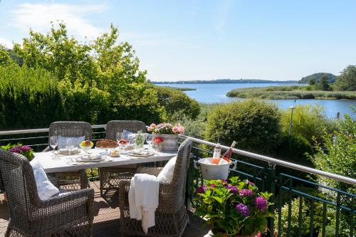 a table on a deck with a view of the water at Weisst Du noch - Gästehäuser & Suiten Rügen in Seedorf
