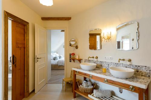 a bathroom with two sinks and two mirrors at Weisst Du noch - Gästehäuser & Suiten Rügen in Seedorf