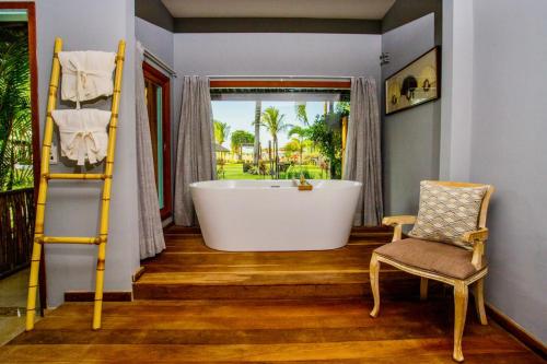 a bathroom with a large tub and a chair at Pousada Mi Secreto in São Miguel do Gostoso