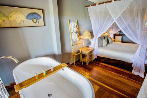 a bathroom with a tub and a bedroom with a bed at Pousada Mi Secreto in São Miguel do Gostoso