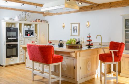 a kitchen with a large island with red bar stools at Weisst Du noch - Gästehäuser & Suiten Rügen in Seedorf