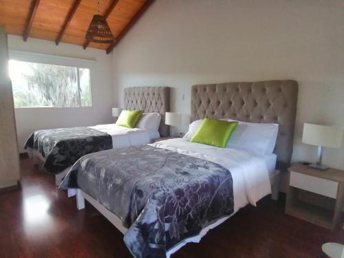 a bedroom with two beds and a large window at HOTEL BOUTIQUE 14 LANCEROS in Paipa
