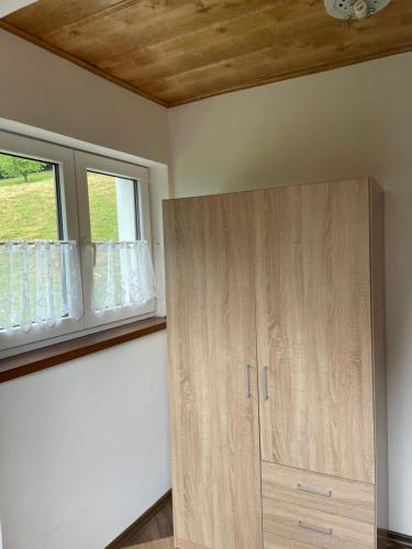 a room with a wooden cabinet and two windows at Apartments Ve dvoře in Velké Karlovice