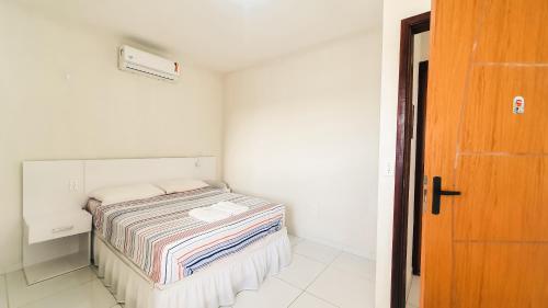 um pequeno quarto branco com uma cama em Pousada Paraiso de Arempebe em Arembepe