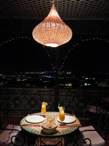 a table with two plates and a chandelier at Riad Pacha Palace in Fès