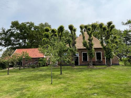 a house with trees in front of a yard at Landelijk gelegen Huisje op erf in Veeningen