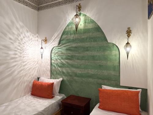 a bedroom with two beds and a green and white wall at Riad Pacha Palace in Fès