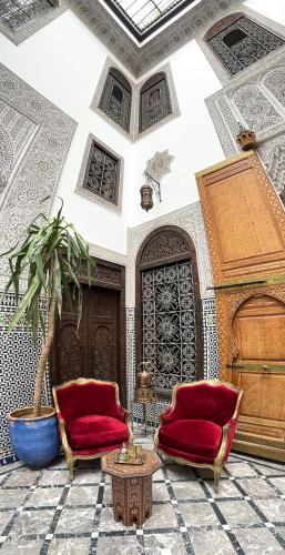 a living room with two chairs and a potted plant at Riad Pacha Palace in Fès