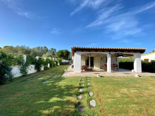 a small white house with a grass yard at La Casa dell Olivo in Castiadas