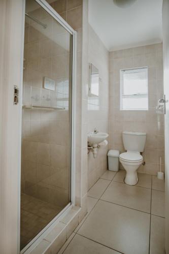 a bathroom with a toilet and a glass shower at Aloha Lodge in Stilbaai