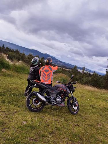 two people sitting on a motorcycle in a field at Hospedaje Casa Blanca in Guatavita