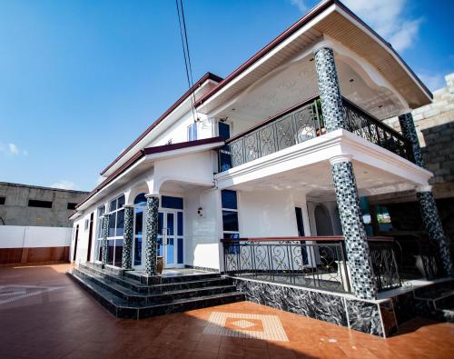 a white house with a balcony on the side at Aduk Guest House Airport City Accra in Otele