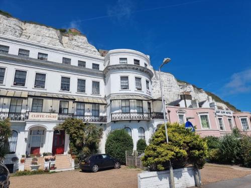 a large white building with a hill behind it at Studio Flat Next to Port and Cliffs in Kent