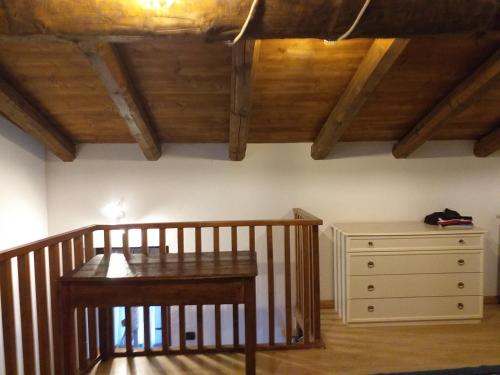 Habitación con mesa, cómoda y techos de madera. en la casa di nonna pina en Roccasparvera