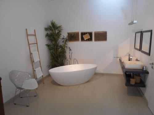 La salle de bains est pourvue d'une grande baignoire blanche et d'un lavabo. dans l'établissement LUXURY 270M² HOUSE OF CHARACTER IN OLD STONES WITH HEATED POOL, NEAR CALVI, à Calenzana