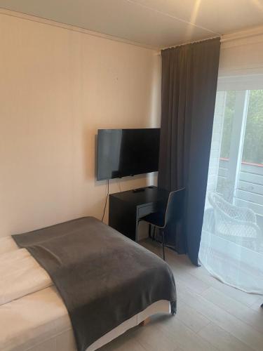 a bedroom with a bed and a desk and a television at Sunde Fjord Hotel, free and easy parking in Solavagen