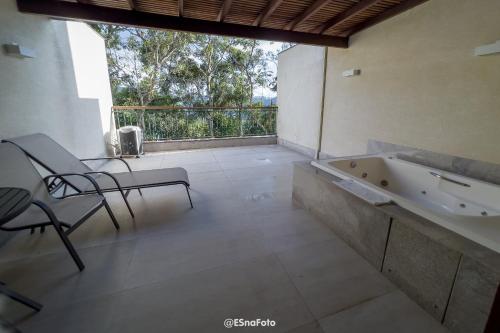 ein Bad mit einer Badewanne, einem Tisch und Stühlen in der Unterkunft Vista Azul Hotel in Pedra Azul