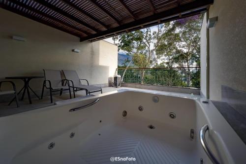 a large white bath tub in a room with a balcony at Vista Azul Hotel in Pedra Azul