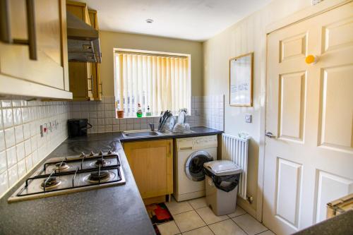 a kitchen with a sink and a stove at Chattel Coventry - Massive Homely space with Garden, dedicated Office space & Free Parking in Longford