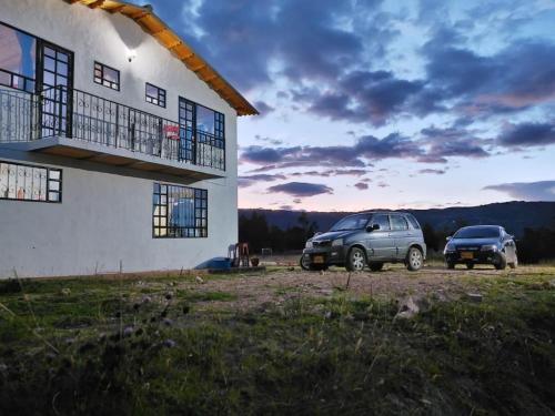 two cars parked in front of a house at Hospedaje Casa Blanca in Guatavita