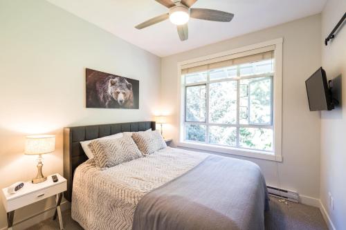 Un dormitorio con una cama con ventilador de techo y una ventana. en Panoramic Views from this gorgeous 2 Bed Property - Village Location, en Whistler