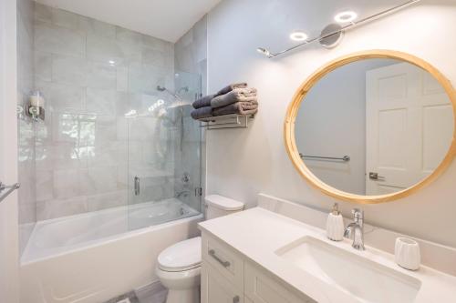 Un baño con lavabo, inodoro y espejo. en Panoramic Views from this gorgeous 2 Bed Property - Village Location, en Whistler