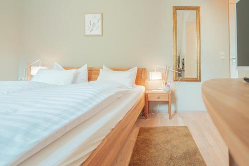a large white bed in a room with a mirror at Hotel Restaurant zur Sonne St. Peter in Sankt Peter