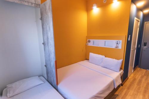 two beds in a small room with yellow walls at Ibis Budget Lorena - Circuito da Fé in Lorena