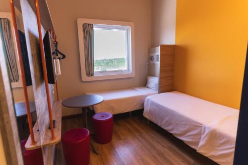 a small room with two beds and a window at Ibis Budget Lorena - Circuito da Fé in Lorena