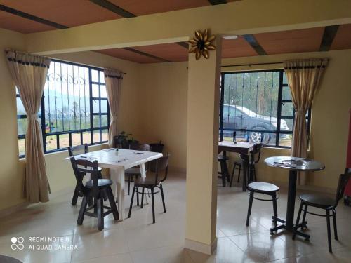 a dining room with tables and chairs and windows at Hospedaje Casa Blanca in Guatavita