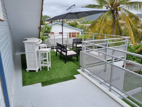 a balcony with a table and chairs and an umbrella at APPARTEMENT SANS SOUCIS in Le Vauclin