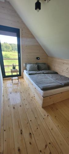 a bed in a wooden room with a large window at Domek drewniany letniskowy całoroczny nad jeziorem 