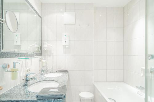 a white bathroom with two sinks and a tub at Hotel Restaurant zur Sonne St. Peter in Sankt Peter