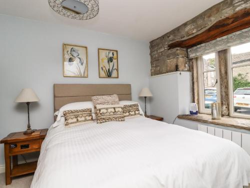 a bedroom with a white bed and two windows at Squint Cottage in Skipton