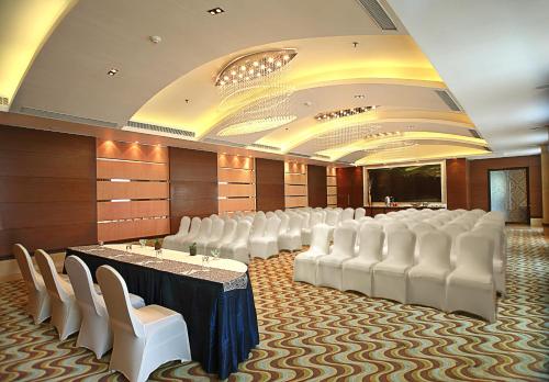 Una sala de conferencias con sillas blancas, una mesa y una pantalla. en Fortune Select SG Highway, Ahmedabad - Member ITC Hotels' Group, en Ahmedabad