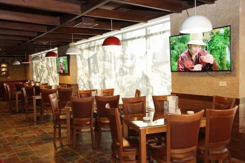 une salle à manger avec des tables et des chaises et une télévision à écran plat dans l'établissement 7 Days Hotel, à Umm Uthainah