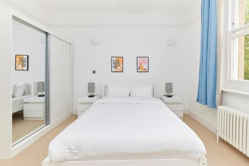 a white bedroom with a large bed and a window at The Woolwich Retreat - Enticing 5BDR House with Parking in Woolwich