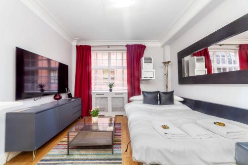 倫敦的住宿－Lovely 1BDR flat in the Heart of London - Mayfair，配有红色窗帘的客房内的两张床