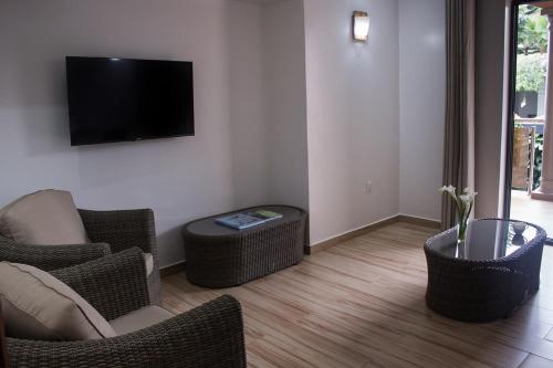 a living room with wicker chairs and a flat screen tv at The Little Hill Boutique Hotel in Kigali