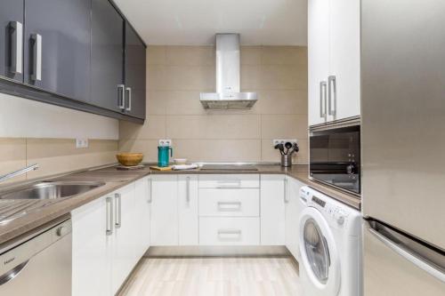 cocina con armarios blancos, lavadora y secadora en Spacious flat puerta del sol, en Madrid