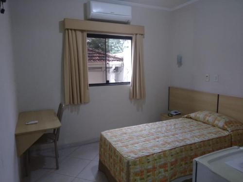 a bedroom with a bed and a desk and a window at SG Palace Hotel in Taubaté