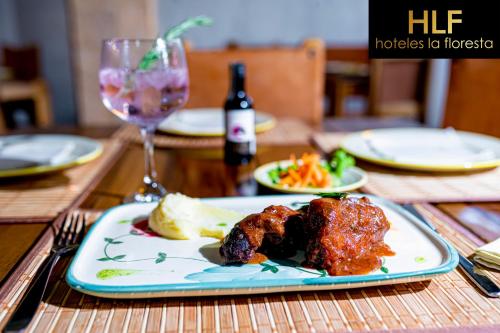 a table with a plate of food and a glass of wine at La Floresta de Cite Hotel in Cite