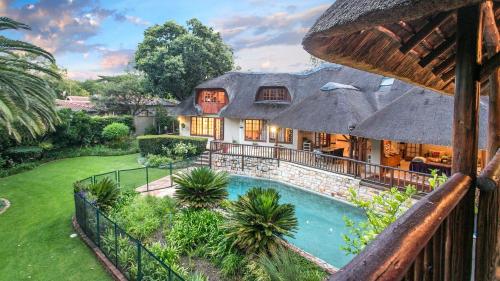 a house with a thatched roof and a swimming pool at Malinga GuestHouse in Sandton