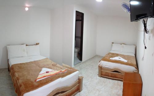 1 dormitorio con 2 camas y TV. en Hotel la Victoria, en San Roque