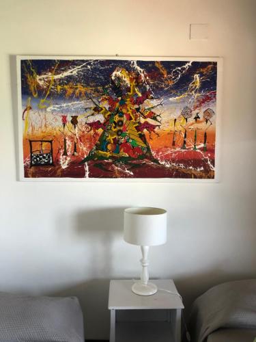 een schilderij aan een muur naast een tafel met een lamp bij bnbthekey 1,2,3 in Olmedo