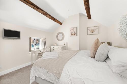 um quarto branco com uma cama grande e uma televisão em Rose End Cottage, a Luxury Getaway em Adlestrop