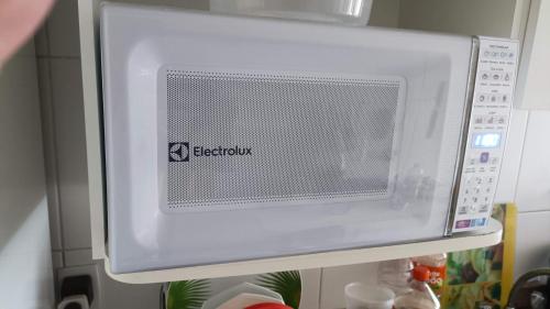 a white microwave oven hanging on a refrigerator at Bora Bora Barra Resort in Rio de Janeiro