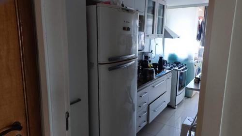 a kitchen with a white refrigerator and a stove at Bora Bora Barra Resort in Rio de Janeiro