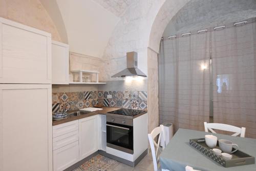 een keuken met witte kasten, een tafel en een fornuis bij Casa vacanze nonna donata in Martina Franca