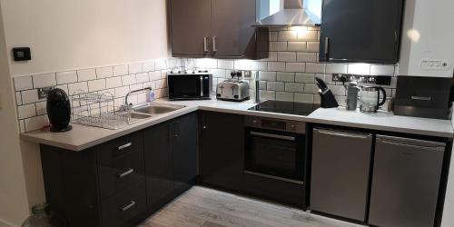 une cuisine avec des armoires noires et des comptoirs blancs dans l'établissement Jaymar, à Fife